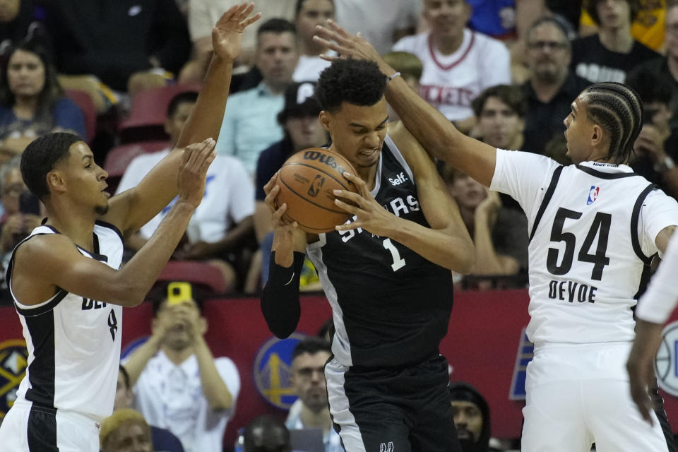 San Antonio Spurs' Victor Wembanyama attempts shot against Portland Trail Blazers' Kris Murray, left, and Portland Trail Blazers' Michael Devoe during the first half of an NBA summer league basketball game Sunday, July 9, 2023, in Las Vegas. (AP Photo/John Locher)