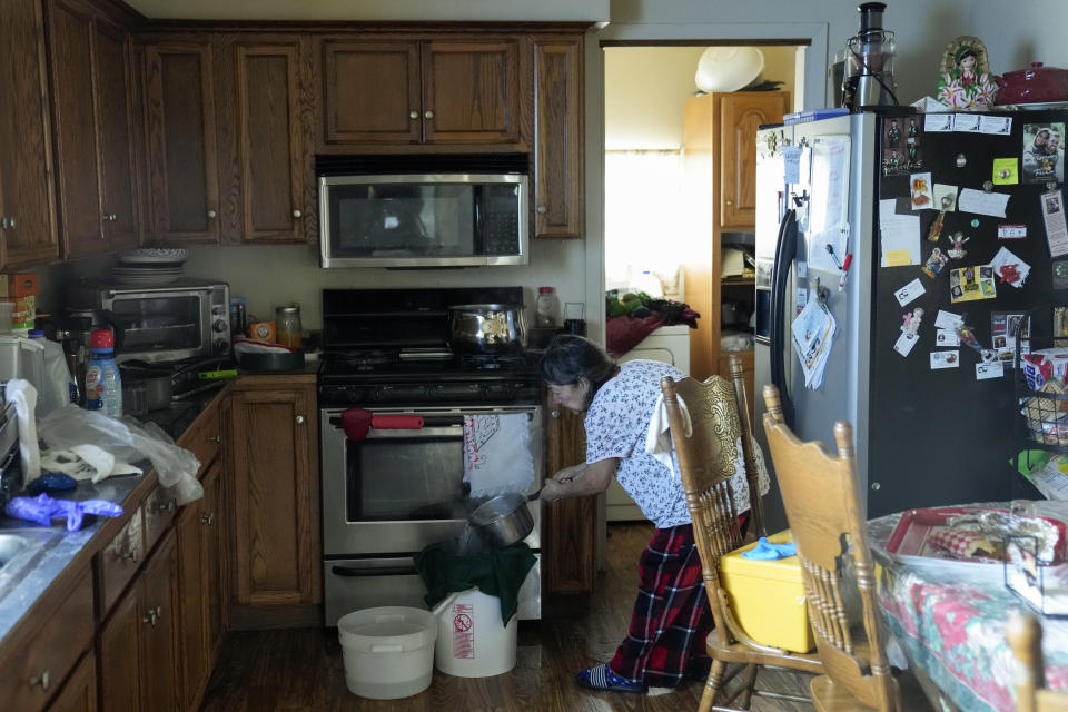 Celia Magdaleno strains boiled water before giving her husband a bath following an earthquake in Rio Dell, Calif., Wednesday, Dec. 21, 2022. Magdaleno's husband is undergoing dialysis treatment and said is crucial for him to be clean before receiving treatment to avoid infections. (AP Photo/Godofredo A. Vásquez)