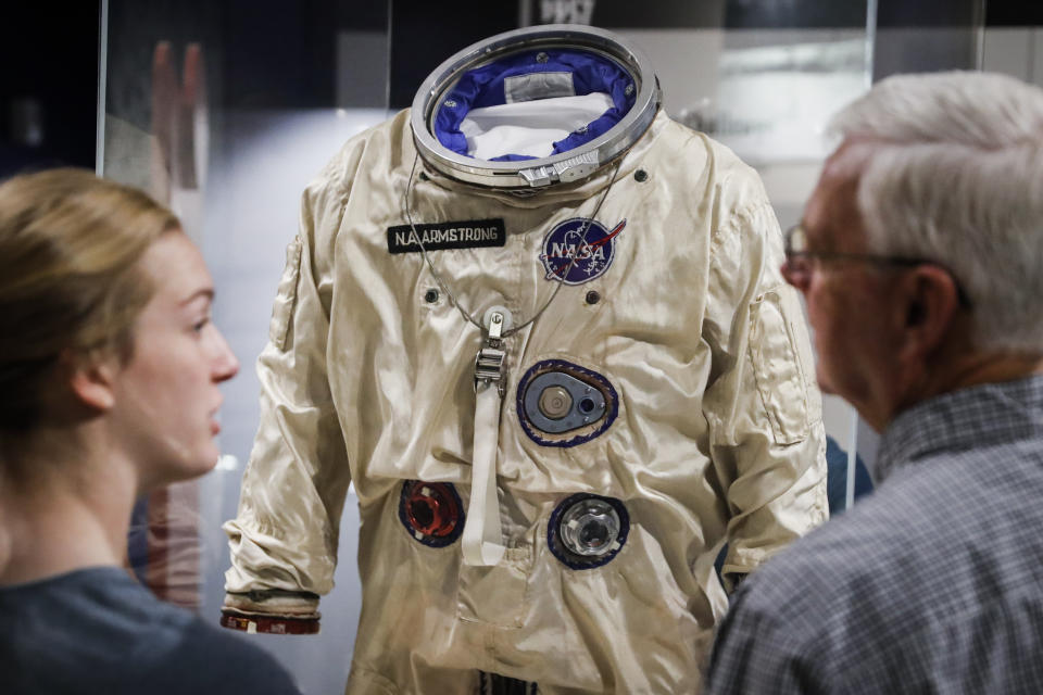 Visitors stand before the spacesuit worm by astronaut Neil Armstrong that was used on his Gemini VIII mission at the Armstrong Air & Space Museum, Wednesday, June 26, 2019, in Wapakoneta, Ohio. Neil Armstrong helped put Wapakoneta on the map July 20, 1969, when he became the first human to walk on the moon. The late astronaut remains larger than life in the city 60 miles (96.56 kilometers) north of Dayton, where visitors are greeted by the space base-shaped top of the space museum named for him as they exit Interstate 75. (AP Photo/John Minchillo)