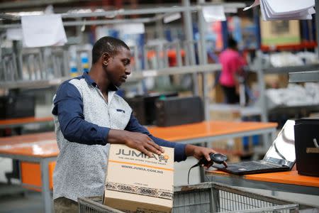 A man works online as he holds a branded cardboard box at a warehouse for an online store, Jumia in Ikeja district, in Nigeria's commercial capital Lagos June 10, 2016.REUTERS/Akintunde Akinleye
