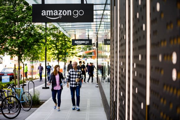 Two people walking past Amazon Go store