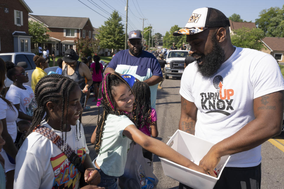 Quientest Vinson, right, of Turn Up Knox hands out candy to children during the Lonsdale Neighborhood Homecoming celebration Saturday, Aug. 5, 2023 in Knoxville, Tenn. The organization is a centerpiece of Knoxville's attempt to follow a science-based playbook to fight a surge in fatal and non-fatal shootings. (AP Photo/George Walker IV)