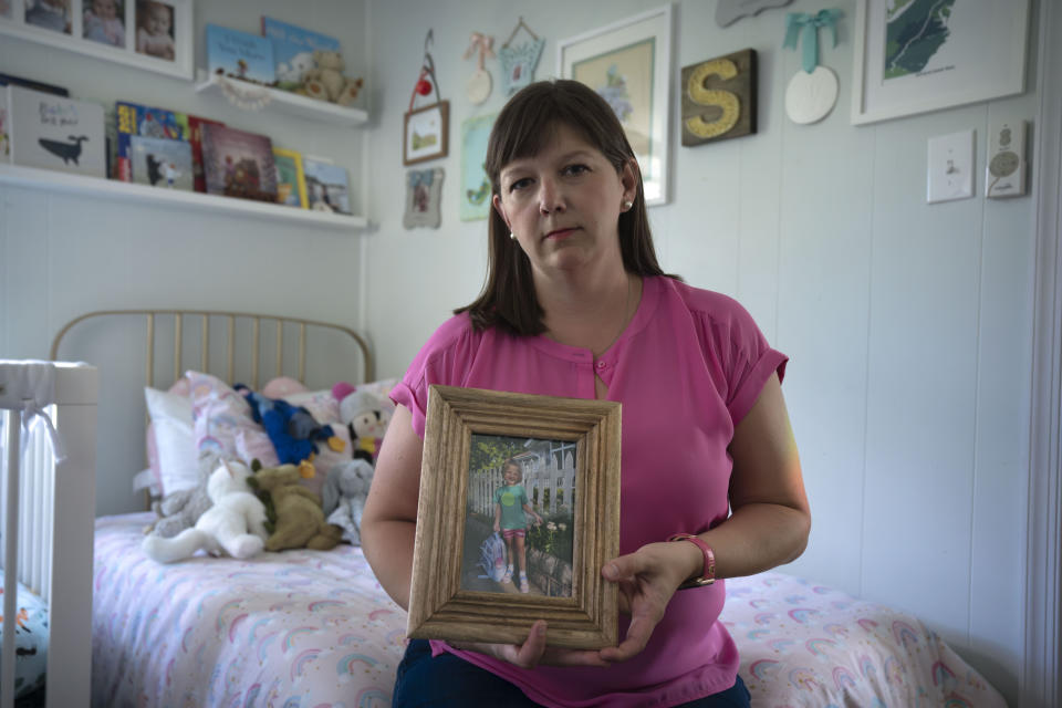 Jessica Riester Hart sits on her daughter's bed as she holds a photo of her daughter, 5-year-old Allie Hart, who was struck and killed in 2021 by a driver while riding her bicycle in a crosswalk near their home, Thursday, Sept. 14, 2023, in Washington. (AP Photo/Mark Schiefelbein)