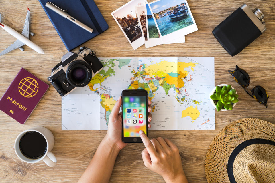 İstanbul, Turkey - August 8, 2018: Woman hands holding a smart phone on a wooden desk with travel accessories. The smart phone is an iPhone 8. iPhone is a touchscreen smartphone developed by Apple Inc.