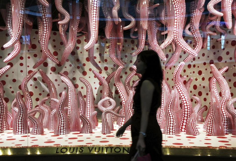 In this photo taken Tuesday Aug. 7, 2012, shopper walks past a window display of Japanese artist Yayoi Kusama's design at a Louis Vuitton shop at the Marina Bay Sands in Singapore. Kusama's signature splash of dots has now arrived in the realm of fashion in a new collection from French luxury brand Louis Vuitton - bags, sunglasses, shoes and coats. The latest Kusama collection is showcased at its boutiques around the world, including New York, Paris, Tokyo and Singapore, sometimes with replica dolls of Kusama. (AP Photos/Wong Maye-E)