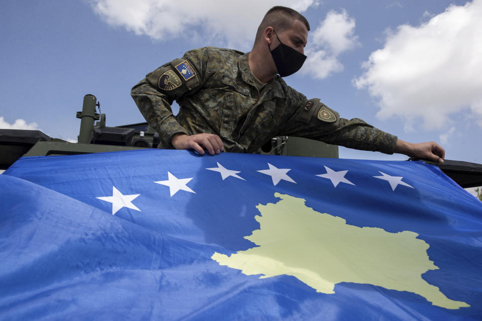 Kosovo Security Force soldier places a Kosovo flag on top of armored security vehicle donated by U.S during a handout ceremony in the military barracks Adem Jashari in capital Pristina on Monday, Aug. 30, 2021. U.S as the main suppliers of Kosovo's defense the U.S donated 55 armored security vehicles to Kosovo Army. (AP Photo/Visar Kryeziu)