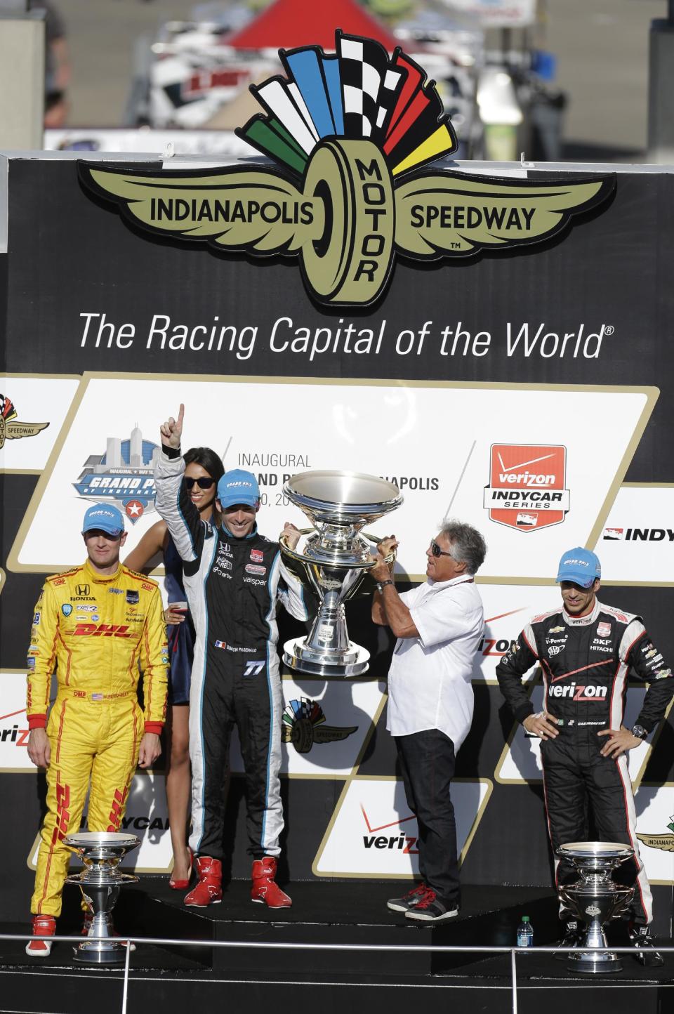 Former Indianapolis 500 champion Mario Andretti, right, helps Simon Pagenaud, of France, hoist the trophy after winning the inaugural Grand Prix of Indianapolis IndyCar auto race at the Indianapolis Motor Speedway in Indianapolis, Saturday, May 10, 2014. Ryan Hunter-Reay, left, finished second and Helio Castroneves, of Brazil, came in third. (AP Photo/Darron Cummings)