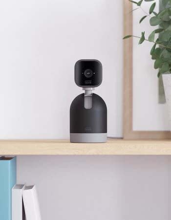 A close up show of a black security camera sitting on a shelf.