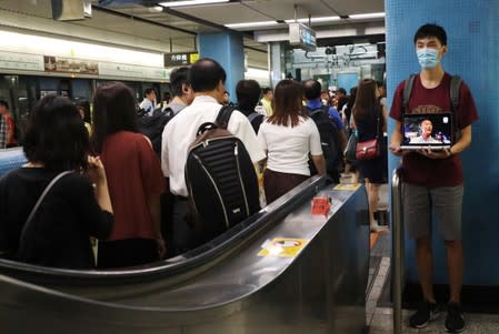 A protester calls people to join further rallies against the government and plays a video of police brutality at Kowloon Tong subway station in Hong Kong