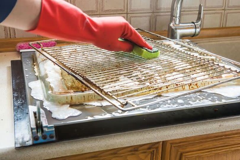 Cleaning the oven. man's hand in household cleaning gloves cleans oven inside.