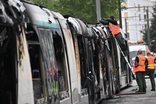 RATP Transport workers dismantle a burnt tram destroyed during protests the previous night in Clamart, southwest of Paris, on 29 June 2023 (AFP via Getty Images)