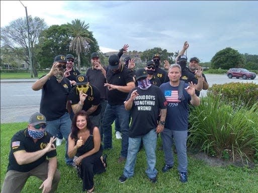 Cindy Falco-DiCorrado (second from bottom left) poses with a group of Proud Boys, who are flashing "white power" signs.