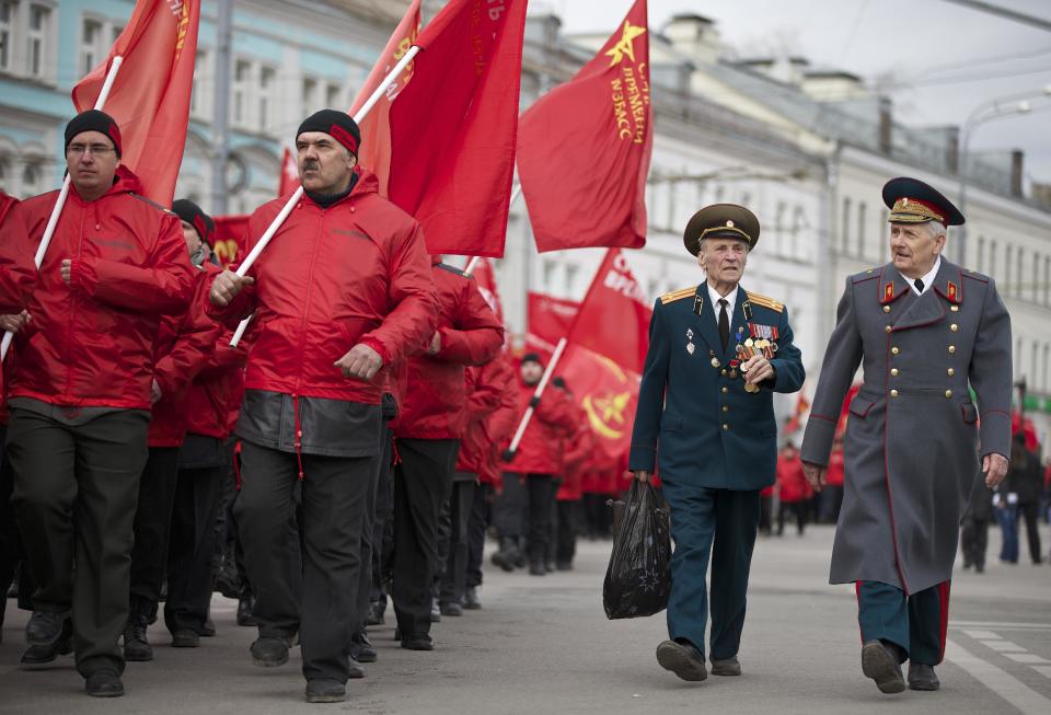 Demonstrators wearing red and two WWII veterans, right, march in support of Kremlin-backed plans for the Ukrainian province of Crimea to break away and merge with Russia, in Moscow, Saturday, March 15, 2014. Large rival marches have taken place in Moscow over Kremlin-backed plans for Ukraine’s province of Crimea to break away and merge with Russia. The marchers belong to a group calling itself the “Essence of Time,” which professes to militate in the interests of social progress in Russia and protect the interests of Russians. (AP Photo/Alexander Zemlianichenko)