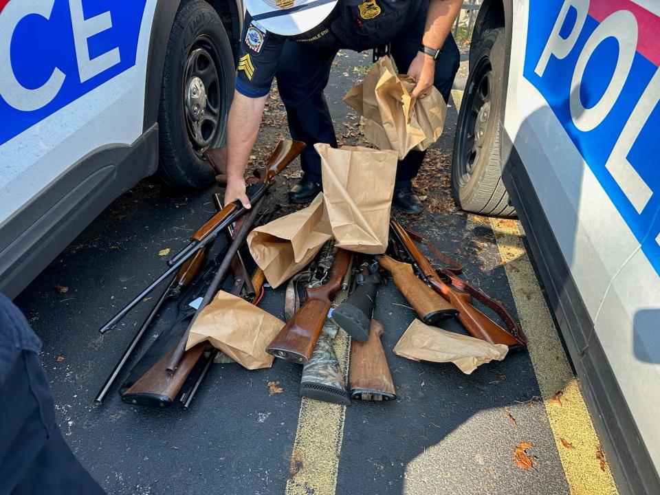 A Columbus police officer handles a collection of rifles purchased during the city's Saturday gun buyback event.