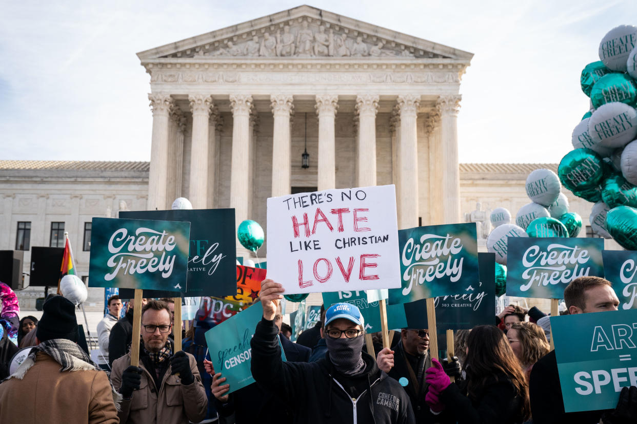 Protesters in front of the Supreme Court hold signs reading: Create Freely and There’s no hate like Christian love.