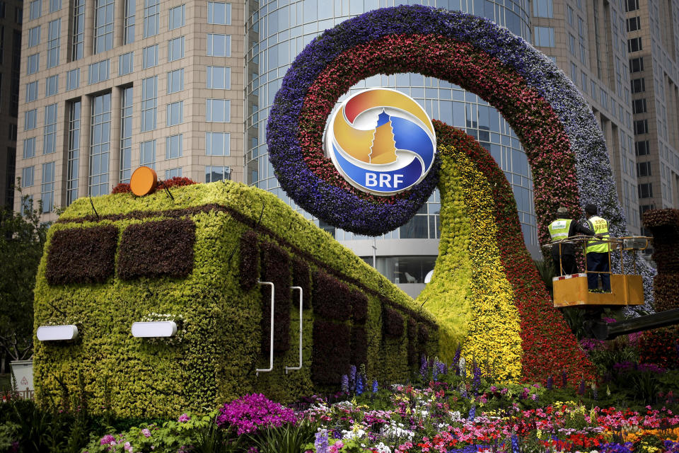 Workers on a platform install flowers on a decoration in a shape of a train for promoting the upcoming Belt and Road Forum in Beijing, Tuesday, April 23, 2019. The Belt and Road Forum which will open by Chinese President Xi Jinping this weekend in the capital city has draw leaders from around the globe. Xi, who has made the initiative a signature policy, agreed last month to seek fairer international trade rules and address the world's economic and security challenges, in what appeared to many as a rebuke to President Donald Trump's protectionist policies. (AP Photo/Andy Wong)