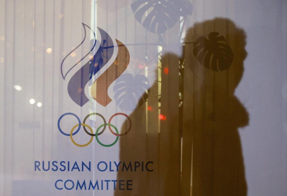 FILE - In this Nov. 18, 2015 file photo a man walking past the Russian Olympic Committee building, casts a shadow on a window in Moscow, Russia. The World Anti-Doping Agency banned Russia on Monday Dec. 9, 2019 from the Olympics and other major sporting events for four years, though many athletes will likely be allowed to compete as neutral athletes. (AP Photo/Pavel Golovkin, file)