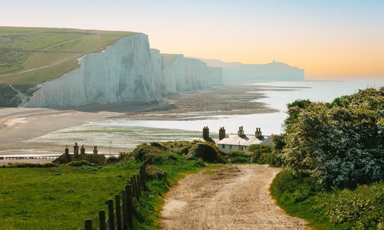 <span>The Seven Sisters cliffs and Cuckmere Haven beach, seen from the Seaford Head path, which passes a terrace of coastguard cottages.</span><span>Photograph: Coldsnowstorm/Getty Images</span>