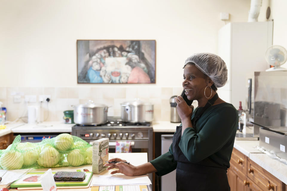 Chief coordinator Glenda Andrew takes a phone call, as she prepares West Indian meals with members of the Preston Windrush Covid Response team, at the Xaverian Sanctuary, in Preston, England, Friday Feb. 19, 2021. Once a week they distribute to people in Preston and surrounding communities in northwestern England that have recorded some of the U.K.’s highest coronavirus infection rates. The meal program grew out of Andrew’s work with Preston Windrush Generation & Descendants, a group organized to fight for the rights of early immigrants from the Caribbean and other former British colonies who found themselves threatened with deportation in recent years. (AP Photo/Jon Super)