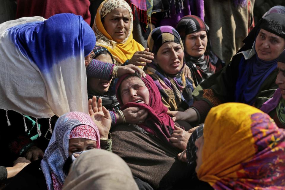 Relatives comfort daughter of Taja begum, a 60-year-old woman who was killed in shootout at her residence in Moul village, 62 kilometers (39 miles) south of Srinagar, Indian controlled Kashmir, Thursday, Feb.23, 2017. Three Indian soldiers and a woman were killed after rebels ambushed soldiers in the disputed region of Kashmir, police said on Thursday. According to them, the attack triggered a brief exchange of gunfire and a stray bullet hit the 60-year-old woman while she was sleeping in her home. (AP Photo/Mukhtar Khan)