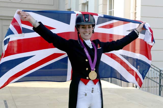 Charlotte Dujardin with a gold medal around her neck which she won at London 2012 and holding a Union Flag aloft. 