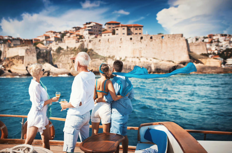 Two couples embracing and looking at a coastal town from a boat