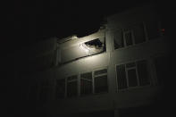 FILE - A Ukrainian police officer uses a flashlight to illuminate a school that was hit by a Russian attack, as he patrols during a night curfew in Kharkiv, Ukraine, Sunday, March 27, 2022. Targeting schools and other civilian infrastructure is a war crime. Experts say wide-scale wreckage can be used as evidence of Russian intent, and to refute claims that schools were simply collateral damage. (AP Photo/Felipe Dana, File)