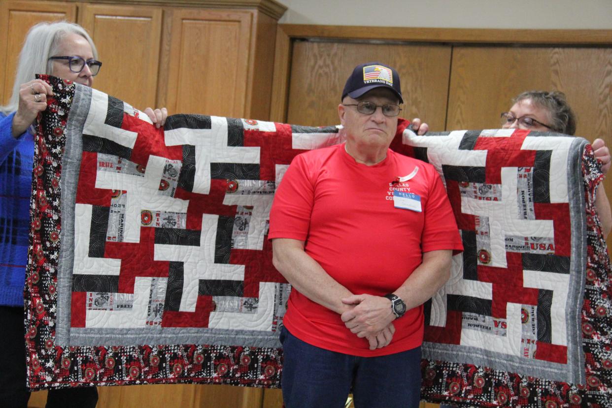 Members of the Perry Piecemakers help wrap Jim Cornelius in a Quilt of Valor during a presentation on on Friday, Nov. 10, 2023, at the Perry Elks Lodge.