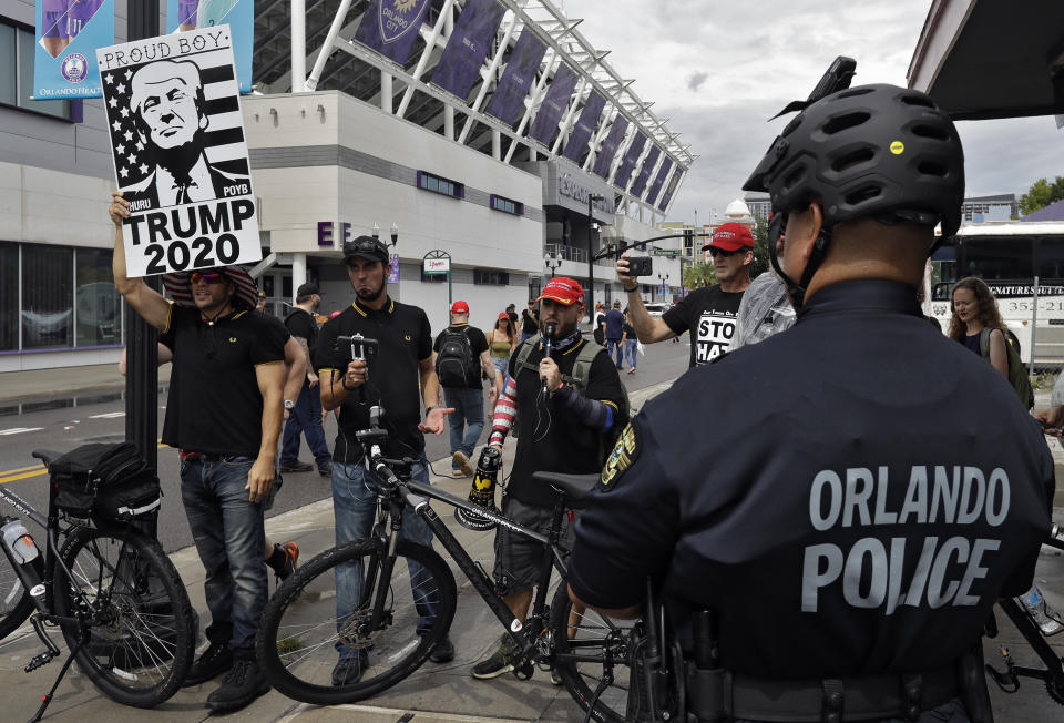 An Orlando, Fla., police officer keeps an eye on a group of President Donald Trump supporters as they shout at protestors Tuesday, June 18, 2019, in Orlando. (AP Photo/Chris O'Meara)