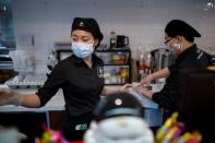 Staff members wearing masks work at a cafe of the French bakery Comptoirs de France in Beijing as the country is hit by an outbreak of the novel coronavirus, in Beijing