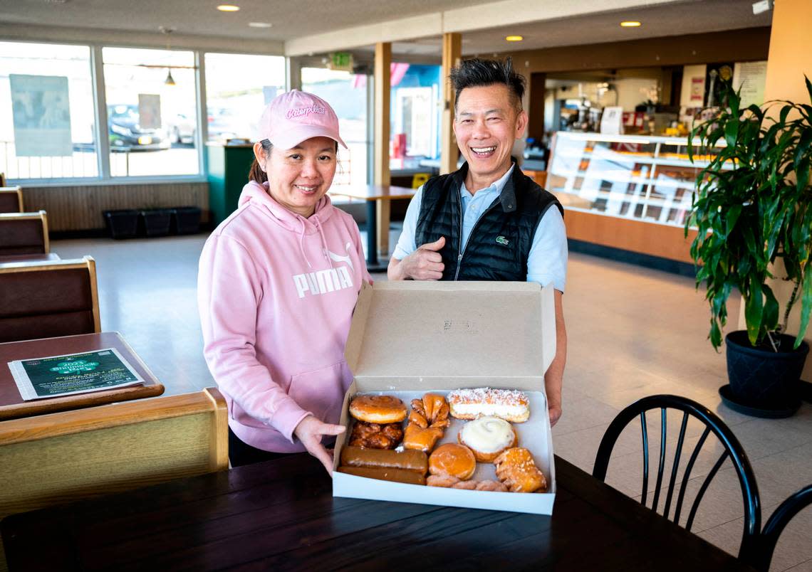 Sam Yam and Kay Oeng pose for a portrait with a box of their hand-made donuts at their shop, Dockside Donuts, at 1112 Puyallup Ave. in Tacoma, Wash., on Feb. 24, 2023. They opened the shop in 2010, but Yam has been making donuts since 1985.