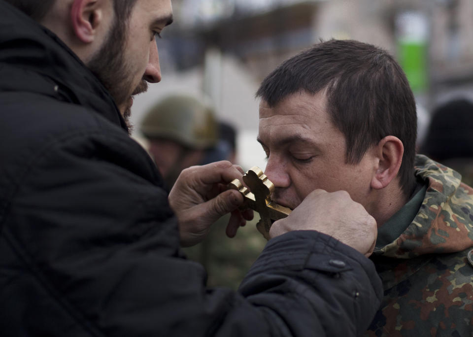 A Ukrainian Orthodox priest blesses volunteer self defense members near Kiev's Independence Square, Ukraine, Sunday, March 16, 2014. Residents of Ukraine's Crimea region on Sunday are voting in a contentious referendum on whether to split off and seek annexation by Russia. (AP Photo/David Azia)