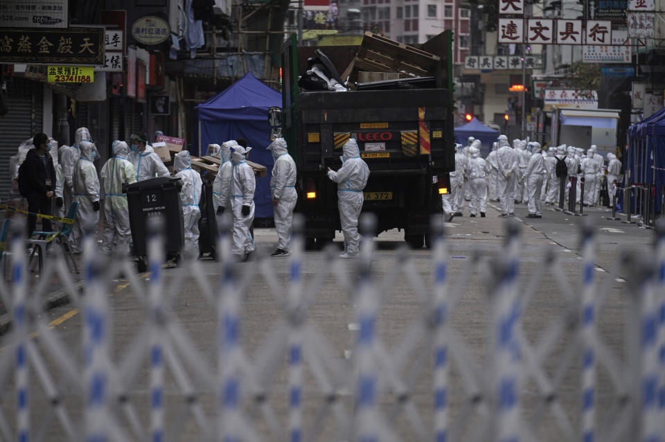 Government workers wearing personal protective equipment gather at the closed area in Jordan district, in Hong Kong, Sunday, Jan. 24, 2021. Thousands of Hong Kong residents were locked down Saturday in an unprecedented move to contain a worsening outbreak in the city, authorities said. (AP Photo/Vincent Yu)