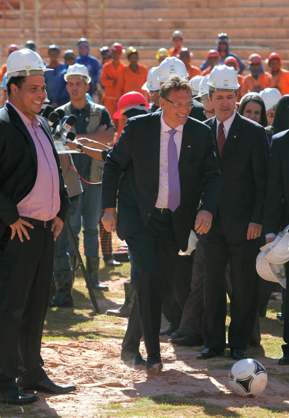 FIFA General Secretary Jerome Valcke, center, prepares to kick a soccer ball as Brazil's former soccer player Ronaldo Lazario, left, looks on during the inspection of ongoing construction at the National Stadium in Brasilia ahead of the 2014 World Cup in Brasilia, Brazil, Thursday, June 28, 2012. The FIFA is inspecting stadiums in Brasilia, Recife and Natal ahead of the 2014 soccer tournament. (AP Photo/Eraldo Peres)