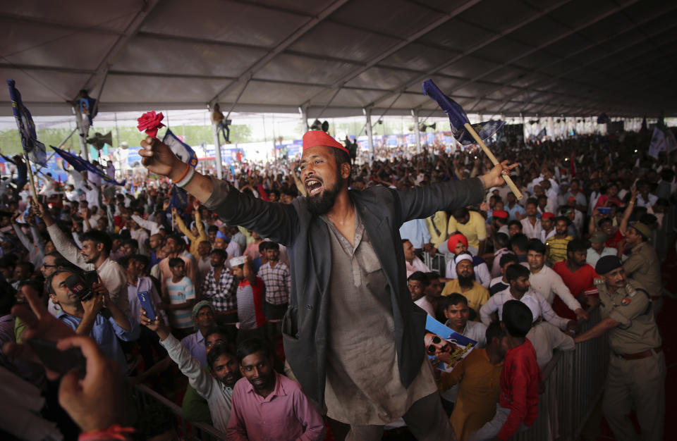 FILE - In this Sunday, April 7, 2019 file photo, a man cheers with a flower in his hand as supporters of Bahujan Samaj Party (BSP), Samajwadi Party (SP) and Rashtriya Lok Dal (RLD) gather during an election rally in Deoband, Uttar Pradesh, India. The final phase of India’s marathon general election will be held on Sunday, May 19. The first of the election’s seven staggered phases was held on April 11. Vote counting is scheduled to start on May 23. India has 900 million eligible voters. (AP Photo/Altaf Qadri, File)