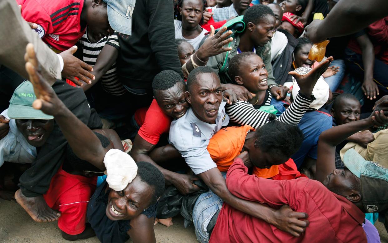Residents desperate for a planned distribution of food for those suffering under Kenya's coronavirus-related movement restrictions at a district office in the Kibera slum, Nairobi - Brian Inganga/AP