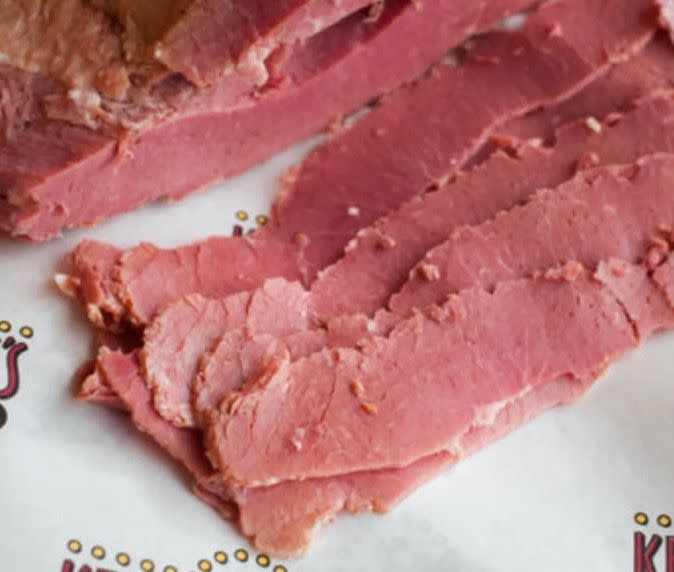 <p><a href="https://www.goldbelly.com/foods/corned-beef?utm_source=blog&utm_medium=pastrami+vs+corned+beef&utm_campaign=corned+beef" rel="nofollow noopener" target="_blank" data-ylk="slk:Corned beef;elm:context_link;itc:0;sec:content-canvas" class="link rapid-noclick-resp">Corned beef</a> is a deli meat made from brisket, located near the cow’s lower chest. Corned beef is cured, brined with a variety of spices, and then boiled to super-tender perfection. </p><p class="has-text-align-left">Corned beef also can trace its roots to Eastern Europe, although it’s also commonly found in Ireland. Corned beef is most commonly served with cabbage (in the traditional Irish preparation) or on rye bread with a schmear of mustard to make one of the most popular Jewish deli sandwiches.</p><span class="copyright"> Kenny & Ziggy’s Delicatessen </span>