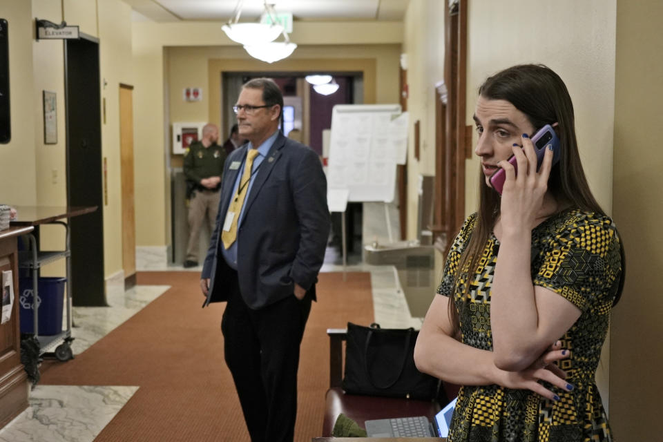 CORRECTS FIRST NAME TO MATT, NOT MARK REGIER - State Rep. Zooey Zephyr speaks on the phone after House Speaker Matt Regier told her she could not work from the hallway just outside the main chamber of the House, Thursday, April 27, 2023 in Helena, Mont. Zephyr was barred from participating on the House floor as Republican leaders voted Wednesday to silence her for the rest of 2023 session after she protested GOP leaders' decision earlier in the week to silence her. (AP Photo/Brittany Peterson)
