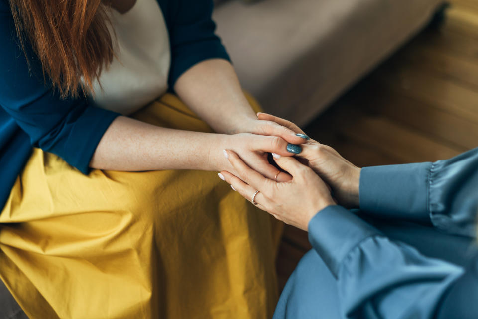 Two individuals holding hands, offering support and comfort in a close-up interaction