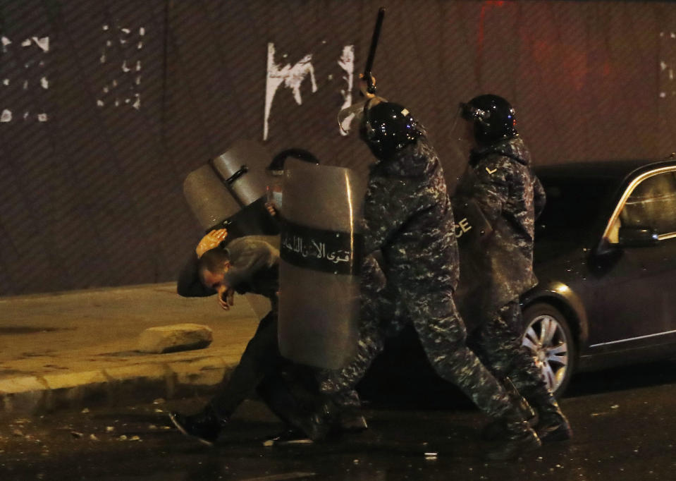 Riot police officers beat an anti-government protester during a protest near the parliament square in downtown Beirut, Lebanon, Saturday, Dec. 14, 2019. The recent clashes marked some of the worst in the capital since demonstrations began two months ago. The rise in tensions comes as politicians have failed to agree on forming a new government. (AP Photo/Hussein Malla)