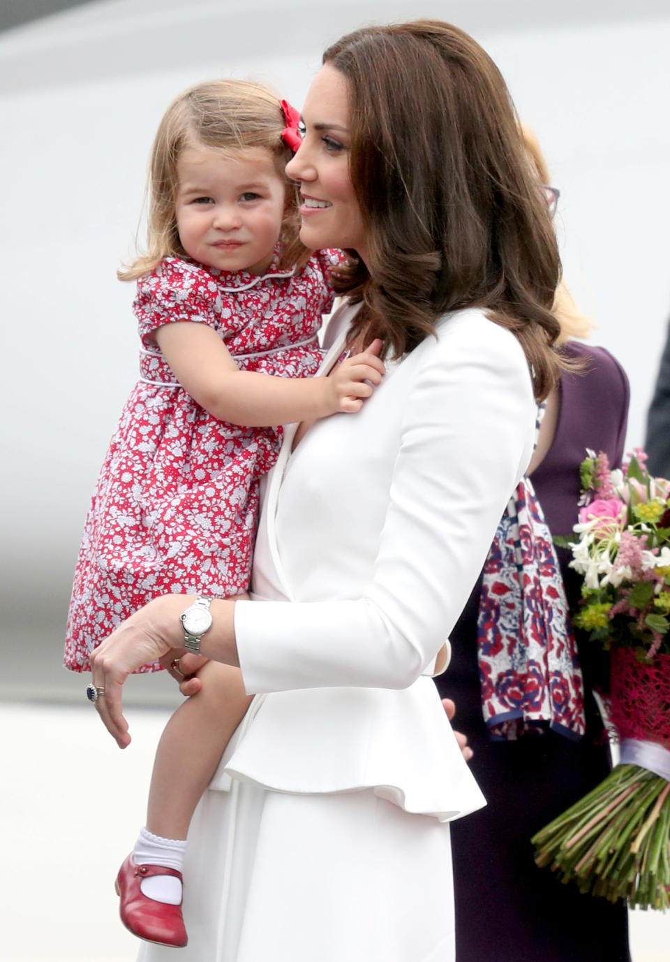 <p>Charlotte smiled for the cameras upon landing in Poland for a royal tour. The 2-year-old looked adorable in a red and white floral dress and matching Mary Janes while resting in mom's arms.</p>