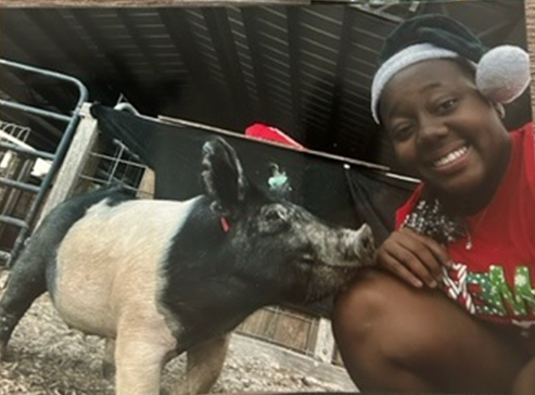 Timiaya Clark poses with Bella B. Swine, the pig she raised as part of special program affiliated with the South Florida State Fair.
