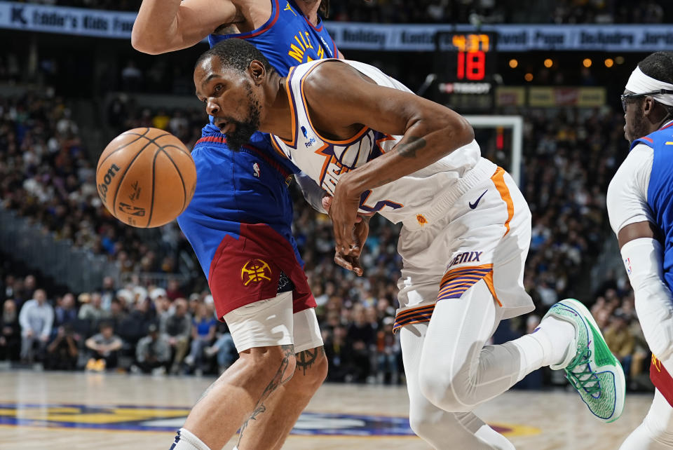 Phoenix Suns forward Kevin Durant, front, loses control of the ball while driving on Denver Nuggets forward Aaron Gordon during the first half of an NBA basketball game Tuesday, March 5, 2024, in Denver. (AP Photo/David Zalubowski)