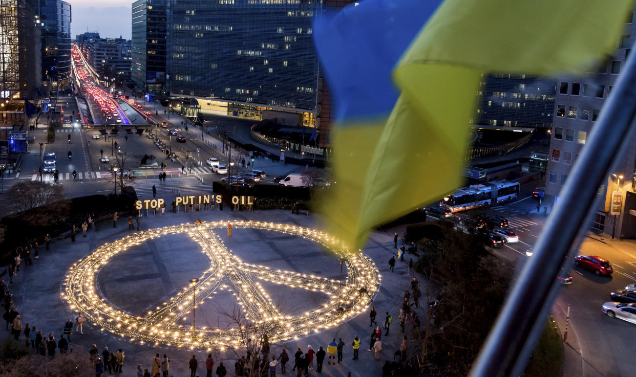 People stand around a giant peace sign with the message 