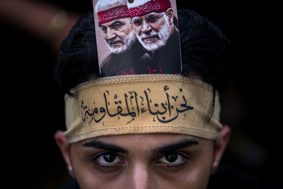 A Hezbollah supporter with portraits of slain Iranian Revolutionary Guard Gen. Qassem Soleimani, left, and slain Iraq's Popular Mobilization forces commander Abu Mahdi al-Muhandis, poses for a photograph while he listens to the story of Ashoura, the Shiite Muslim commemoration marking the death of Imam Hussein, the grandson of the Prophet Muhammad, at the Battle of Karbala in present-day Iraq in the 7th century, in the southern suburbs of Beirut, Lebanon, Saturday, July 29, 2023. Arabic reads: "We are the sons of the resistance." (AP Photo/Hassan Ammar)