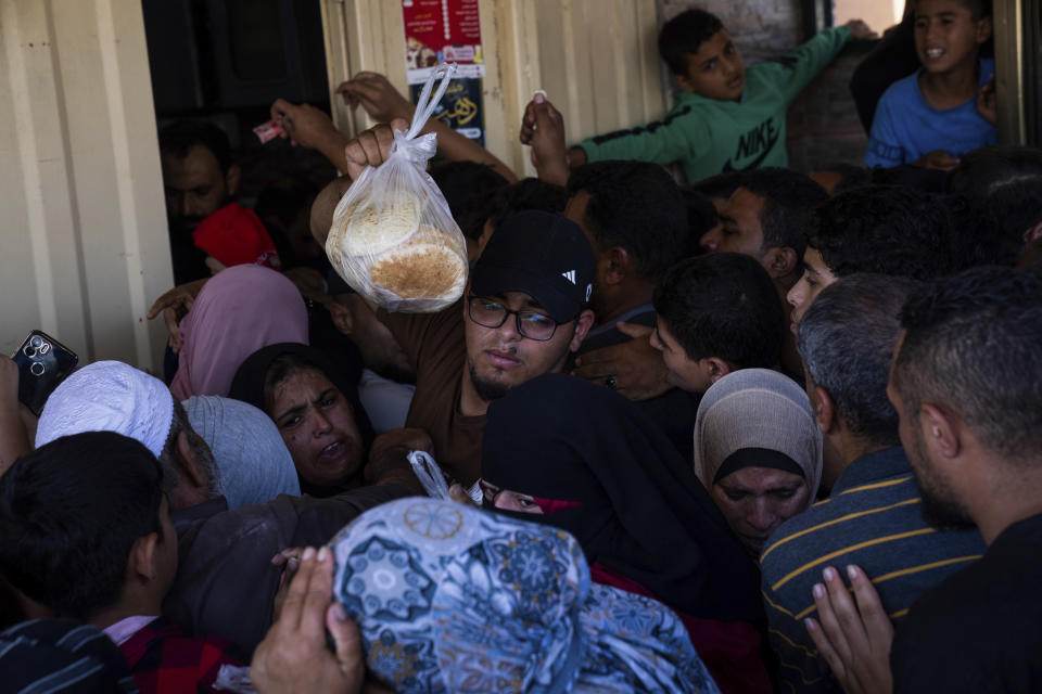 Palestinians crowding to buy bread from a bakery, in Khan Younis, Gaza Strip, Sunday, Oct, 15, 2023. Israel has cut off the flow of food to Gaza after a Hamas attack last week killed 1,300 people and Israel's retaliatory strikes killed more than 2,300 Palestinians. (AP Photo/Fatima Shbair)