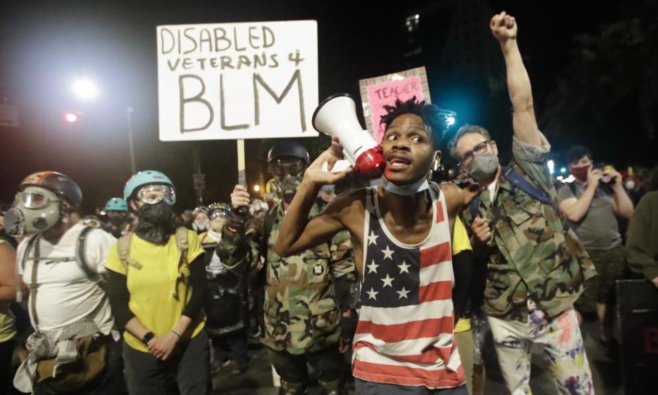 A demonstrator shouts slogans using a bullhorn next to a group of military veterans during a Black Lives Matter protest in Portland.