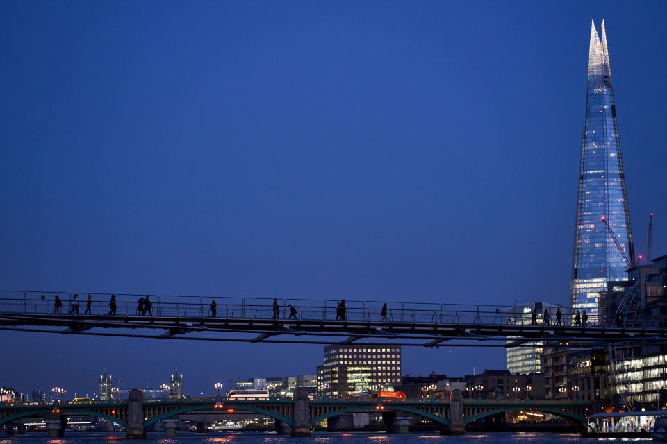 A view toward's the shard as pedestrian's walk over the millennium bridge at dusk