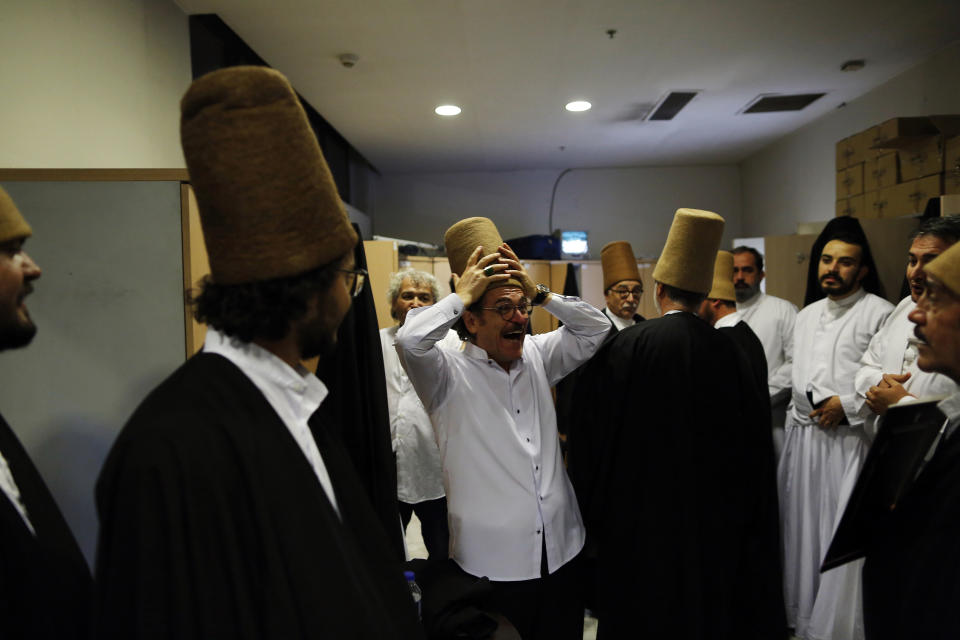 In this photo taken on Sunday, Dec. 16, 2018, whirling dervishes of the Mevlevi order enjoy a light moment in the locker room prior to a Sheb-i Arus ceremony in Konya, central Turkey. Every December the Anatolian city hosts a series of events to commemorate the death of 13th century Islamic scholar, poet and Sufi mystic Jalaladdin Rumi. (AP Photo/Lefteris Pitarakis)