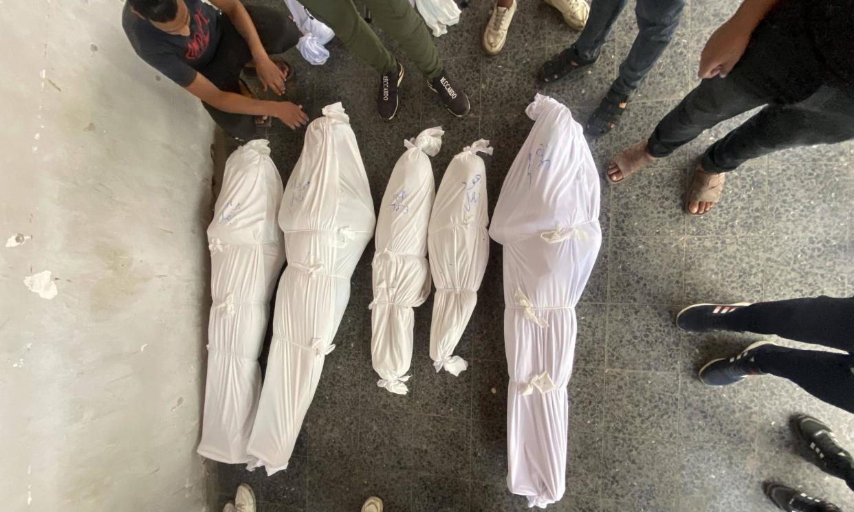 <span>Relatives of the Basal family stand with their shrouded bodies after they were killed in Israeli attacks on Gaza City on Monday.</span><span>Photograph: Hadi Daoud/Sipa/Rex/Shutterstock</span>